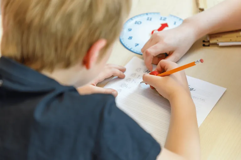 Ergotherapie für Kinder – Kind übt Schreiben mit der Lernuhr