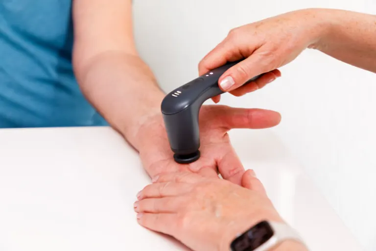 Behandlung der Hand mit einem Vibrationsgerät