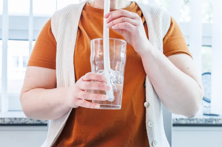Patientin hält ein Glas Wasser für eine Schluckübung in beiden Händen