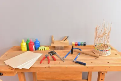 Werkbank mit Hammer, Zange, Farben und einem angefangenen Korbgeflecht
